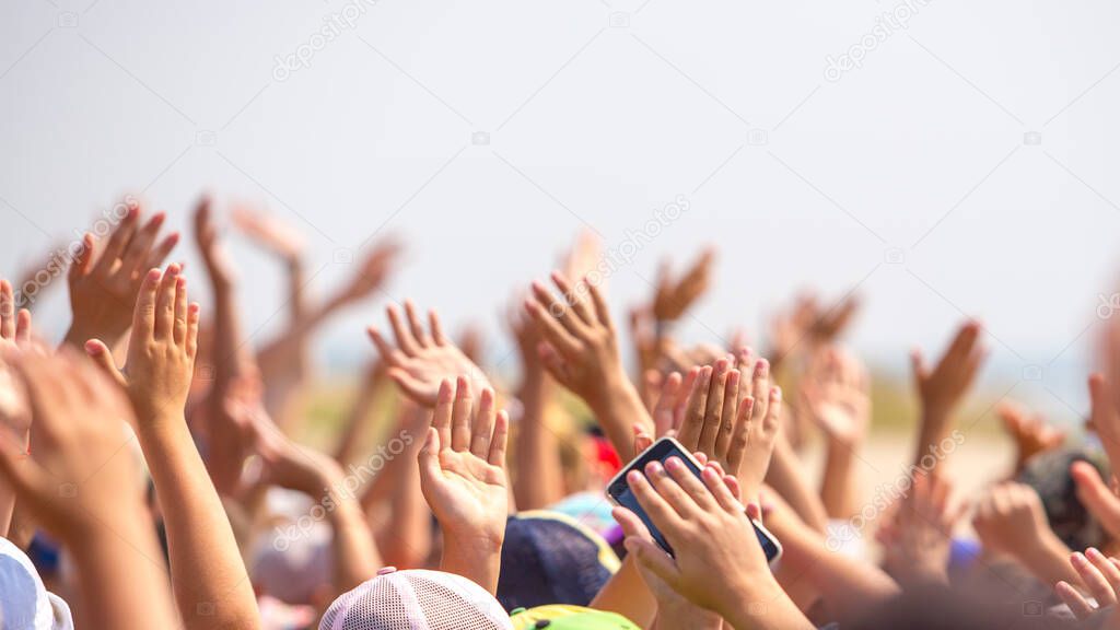 group of happy young people with hands up to the sky