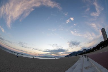 Mavi gökyüzü ve bulutları olan bir plajda gün batımı manzarası