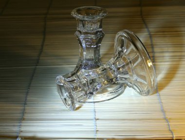 Farklı renklerde cam ve kristal tabaklar, yeşil, mavi, şeffaf şarap bardakları ve masa üzerinde peçeteler ve çerçevelerle renkli cam toplarla şamdanlar.