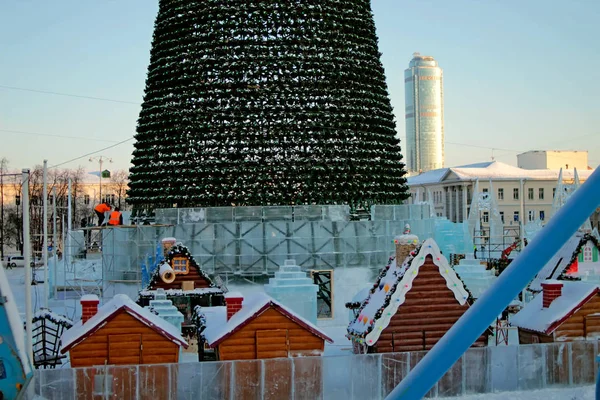 Urban development in winter with administrative residential buildings and the device of the ice town with attractions of swings houses and Christmas trees