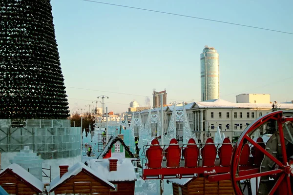 Urban development in winter with administrative residential buildings and the device of the ice town with attractions of swings houses and Christmas trees
