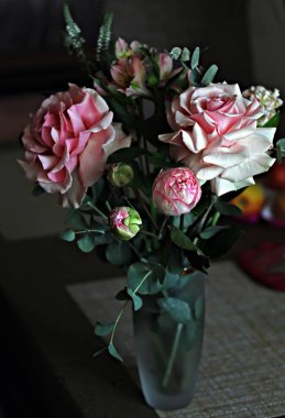 Bir buket gül ve beyaz çiçekler, parlak yeşil yapraklı muhteşem pembe ve beyaz güller, açılmamış çiçeklerin narin tomurcukları ve güller