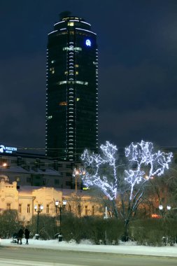 Şehrin şehir gece manzarası, binaların aydınlatılmış mimarisi ve merkezde buz figürleri ve cazibeleriyle yeni yıl kutlamaları.