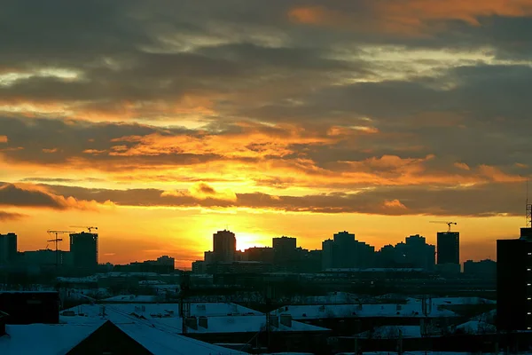 Winter morning with the rising sun and clouds in yellow, orange and red in the city on the background of development