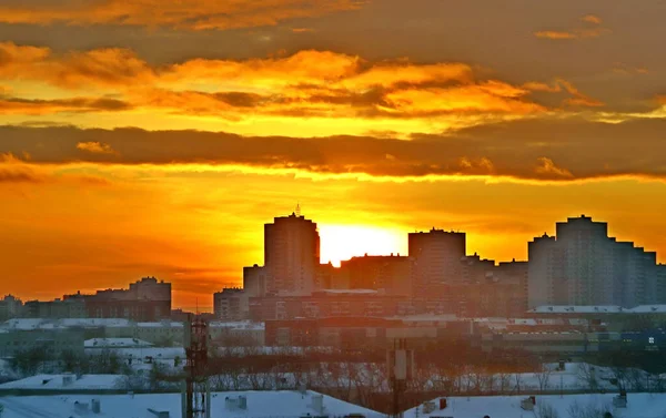 Winter morning with the rising sun and clouds in yellow, orange and red in the city on the background of development