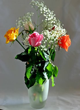 İçi ve çiçekli bir vazo ve bir gül sarı, beyaz, kırmızı, pembe ve Burgundy cam bir vazoda masanın üstünde.