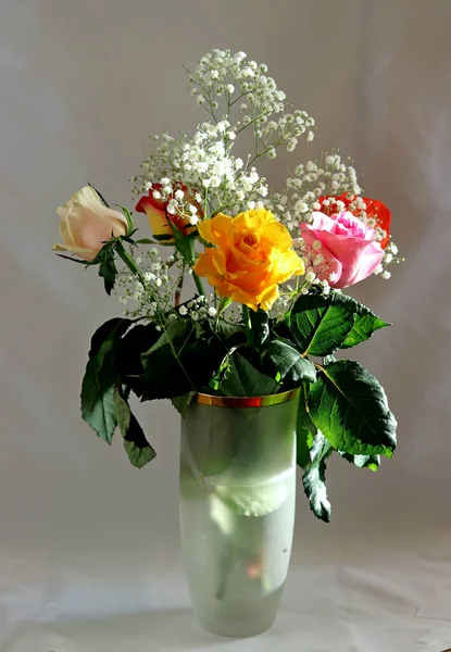 İçi ve çiçekli bir vazo ve bir gül sarı, beyaz, kırmızı, pembe ve Burgundy cam bir vazoda masanın üstünde.