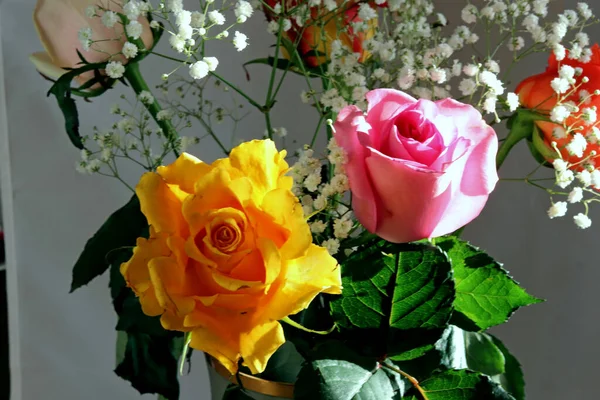 Interior and flowers in a vase with a bouquet and one rose yellow, white, red, pink and Burgundy in a glass vase on the table