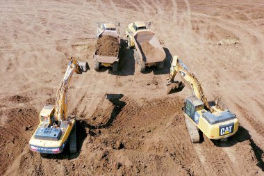Aerial image of a Vast excavation site with multiple heavy industry vehicles working, such as Excavators, Articulated hauler trucks and more. clipart