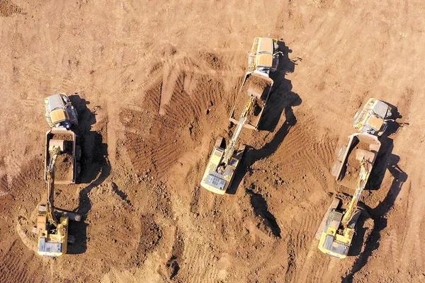 掘削機 関節式運搬車などの複数の重工業車両が動作する広大な掘削現場の空中像 — ストック写真