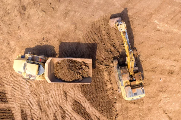 Kazıcıların eklemli nakliye kamyonlarına toprak yüklediği hava görüntüsü