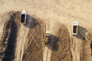 Kazıcıların eklemli nakliye kamyonlarına toprak yüklediği hava görüntüsü