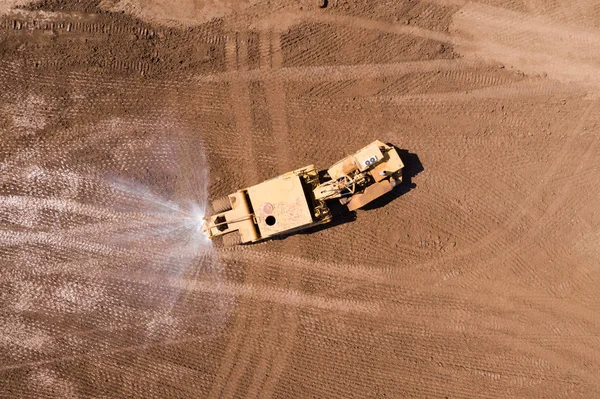 Articulated Water Truck spraying water, Aerial image.