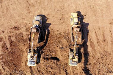 Kazı makineleri toprağı eklemeli nakliye kamyonuna yüklüyor..
