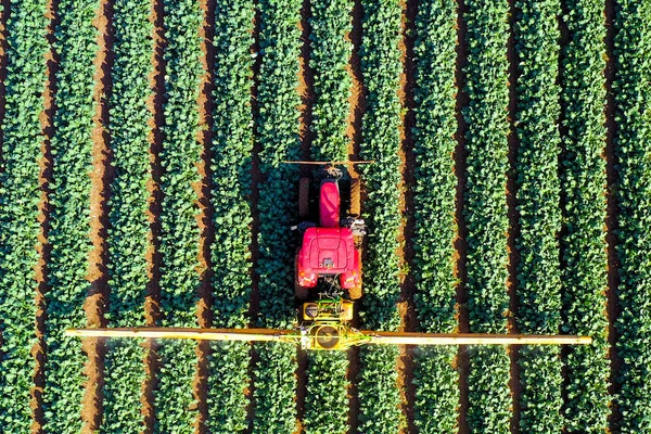 Трактор пестицидов, работающий на большом поле. — стоковое фото