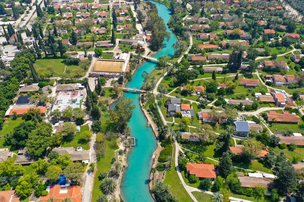 Kibbutz Nir David üzerindeki hava geçidi Amal Nehri kanalı turkuvaz suyu ile doğu ve batı yakasındaki nehir kenarındaki evleri ve palmiye ağaçlarını bölüyor, İsrail.