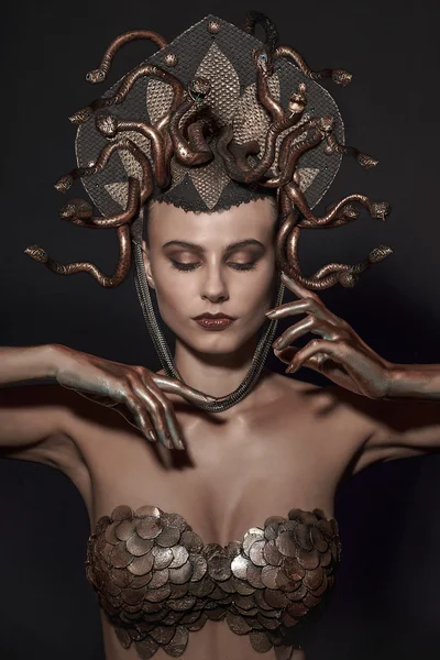 Girl Medusa headdress of gold color on a black background — Stock Photo, Image