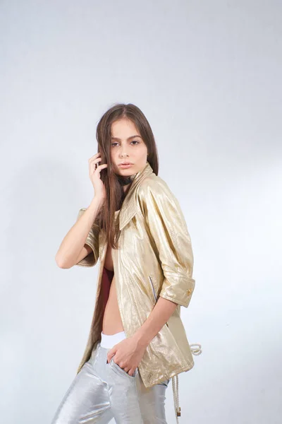 Menina bonita nova em uma jaqueta de ouro e calças de prata no estúdio — Fotografia de Stock