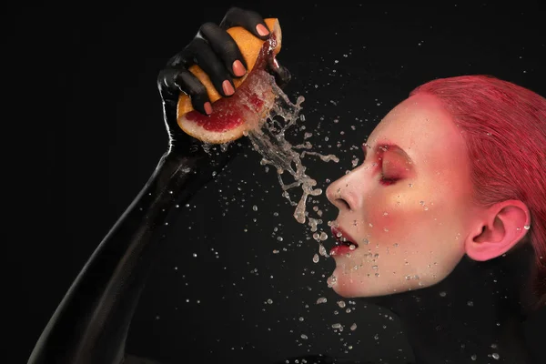 Porträt eines Mädchens mit rotem Make-up und Grapefruit, das in die Kamera blickt — Stockfoto