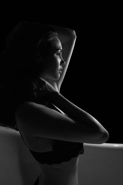 Küvette dinlenirken eğlenen seksi genç bir kadının siyah beyaz portresi.