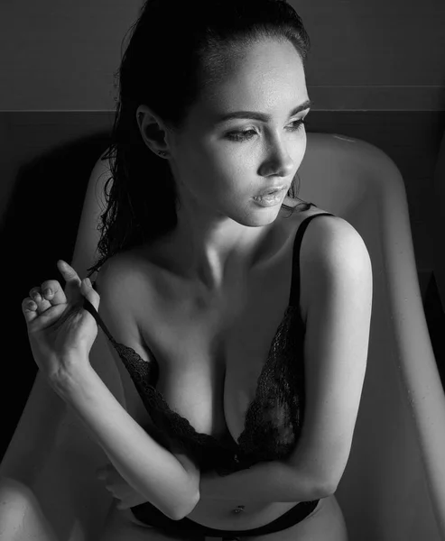 Küvette dinlenirken eğlenen seksi genç bir kadının siyah beyaz portresi.