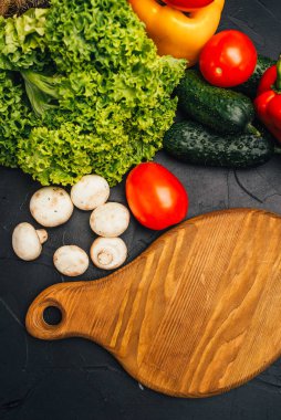 Taze çiğ ve sağlıklı sebzelerin yakın plan görüntüsü ve siyah yüzey üzerinde ahşap tahta.