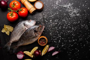 Lezzetli taze balık, limon dilimleri, domatesler ve siyah baharatlar.  