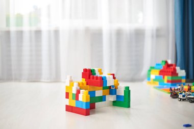 Gri ahşap arka planda parlak renkli plastik yapı taşları. Oyuncak geliştiriyorum. Erken öğrenme. 