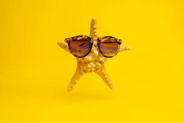 Sarı arka planda güneş gözlüklü komik deniz yıldızının yakın plan görüntüsü