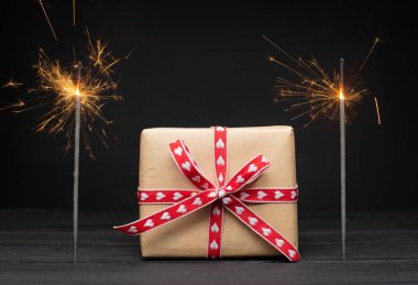 Siyah arkaplanda yanan kıvılcımların ve hediye kutusunun yakın plan görüntüsü