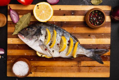 Limon dilimleri ve baharatlarla dilimlenmiş lezzetli taze balıkların üst görüntüsü.