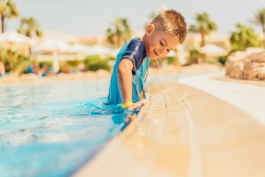 Yaz tatilinde havuzda yüzen sevimli küçük çocuğun yan görüntüsü.  