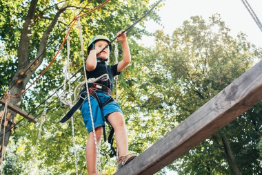 Sevimli mutlu çocuk güneşli bir günde macera parkında eğleniyor.