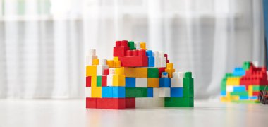 Gri ahşap arka planda parlak renkli plastik yapı taşları. Oyuncak geliştiriyorum. Erken öğrenme. 