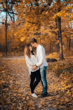 Güz parkında sarılan güzel ve mutlu çiftin yan görüntüsü. 