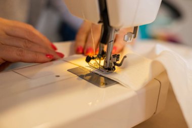 Dikiş makinesi kullanan bir kadının kısmi görüntüsü 