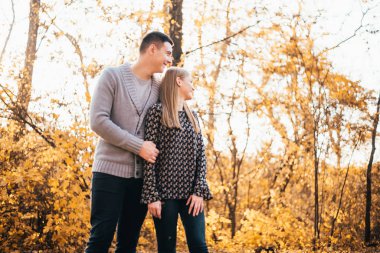 Güz parkında yan yana duran mutlu genç bir çift.