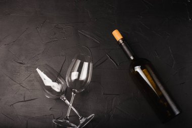 Boş bardakların üst görüntüsü ve siyah arka planda bir şişe şarap.