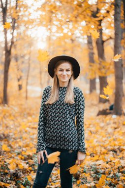 Güz ormanında duran şapkalı güzel bir kadın.
