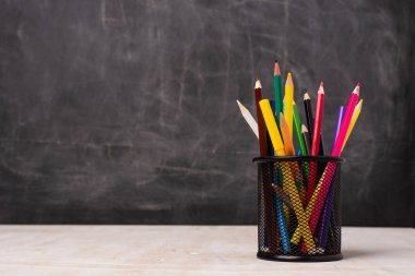 Masadaki okul malzemelerinin yakın görüntüsü ve kopya alanı olan karatahta