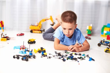 Yerde yatıp plastik oyuncak bloklarıyla oynayan sevimli bir çocuk.