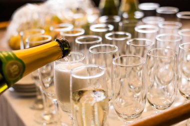 Şampanyayı şişeden bardaklara doldurma manzarası, kutlama konsepti.