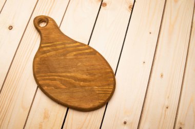 Ahşap doku arkaplanındaki kahverengi kesme tahtasının yakın plan görüntüsü. 