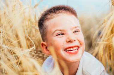 Buğday tarlasında yatan sevimli, mutlu küçük çocuğun yakın çekimi. 