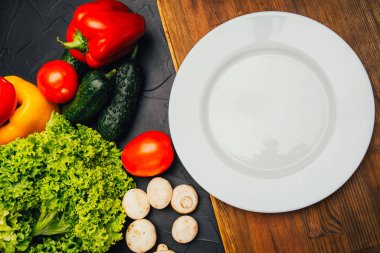 Siyah yüzeydeki taze çiğ ve sağlıklı sebzelerin yakın plan görüntüsü.