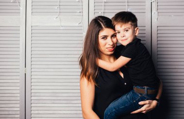 Mutlu genç anne ve sevimli küçük oğlu kameraya sarılıp gülümsüyor.