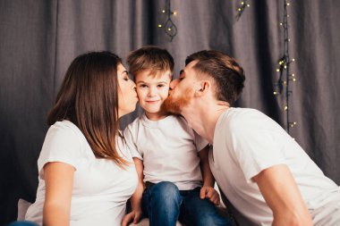 Mutlu ebeveynler küçük sevimli oğlunu öpüyor.