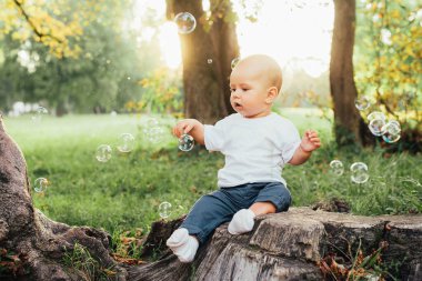 Küçük çocuk yaz parkında oturuyor.