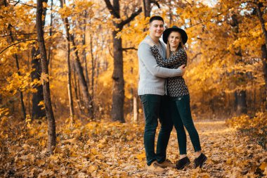 Güz ormanlarında kucaklaşan güzel mutlu genç çift.