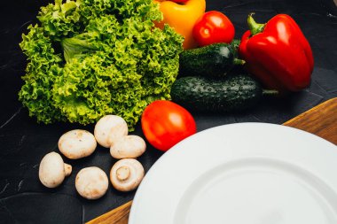 Siyah yüzeydeki taze çiğ ve sağlıklı sebzelerin yakın plan görüntüsü.